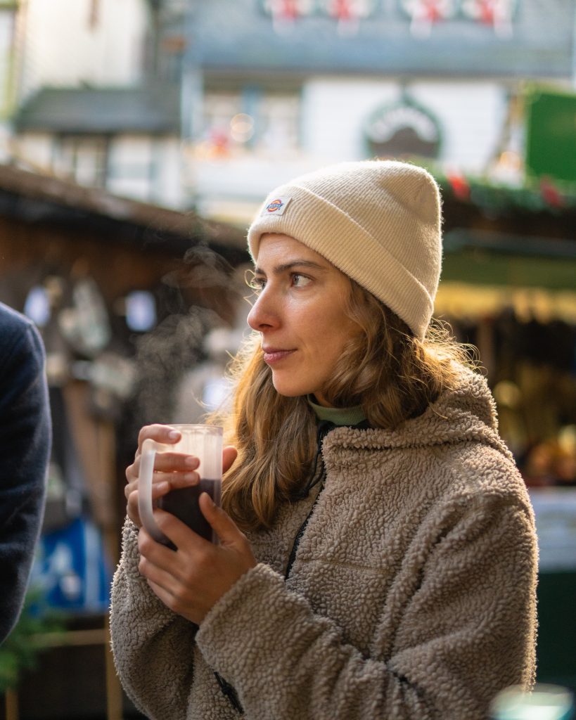 Portrait de profil d'une femme au Marché de Noël de Monschau/Montjoie qui se réchauffe les mains en tenant son vin chaud